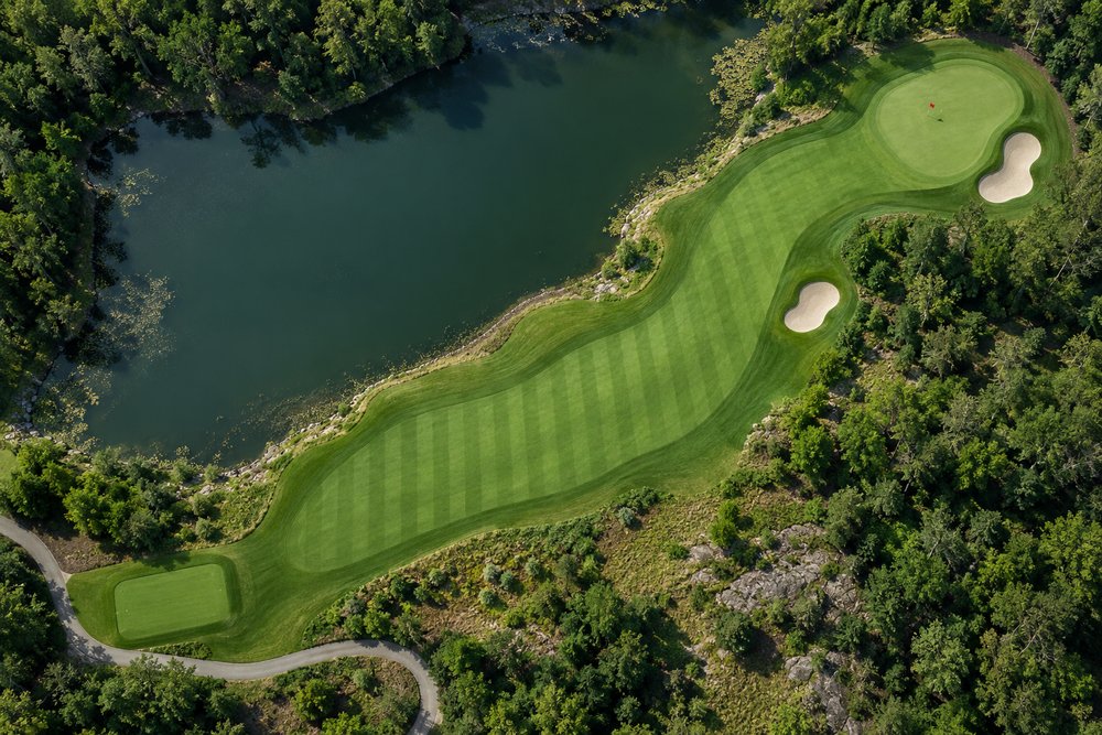 An aerial view of a par three played across water to a green